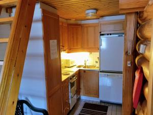una pequeña cocina con armarios de madera y nevera. en Pankkotupa Yrjo en Punkaharju