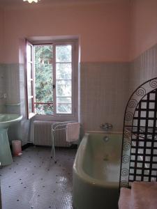 La salle de bains est pourvue d'une baignoire, d'un lavabo et d'une fenêtre. dans l'établissement Chambres d'Hôtes Closerie du Guilhat, à Salies-de-Béarn