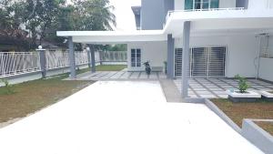 a dog sitting in the front yard of a white house at D'Bangi Villa in Kampong Sungai Ramal Dalam