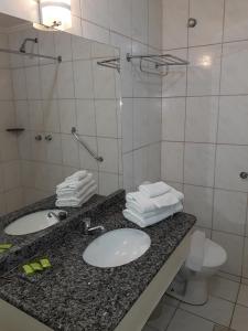 ein Badezimmer mit 2 Waschbecken und einer Dusche mit Handtüchern in der Unterkunft 1307 AP 2 Quartos Shopping , banheira de hidro privativa , bebidas liberadas nas piscinas , e com internet no ap, proximo ao shopping singapura in Caldas Novas