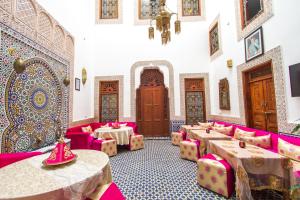 una habitación con mesas rosas y sillas en un edificio en Dar Bab Guissa, en Fez