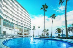 a hotel with a large swimming pool next to palm trees at Seogwipo KAL Hotel in Seogwipo