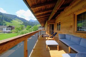 een veranda van een blokhut met een bank en stoelen bij Alpin Penthouse Hollersbach in Hollersbach im Pinzgau