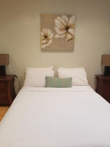 ワーナーズ・ベイにあるTantarra Bed & Breakfastの白いベッド(枕2つ付)と壁画