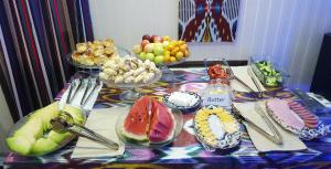 a table topped with bowls of fruit and plates of food at Jahongir Guest House in Samarkand