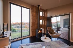 a living room with a fireplace and large windows at StoneTryst Spa Villas in Beechworth