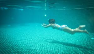 a woman swimming in the water in a pool at Royal Crown Hotel & Spa in Siem Reap