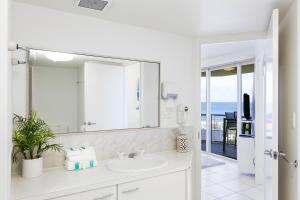 un bagno bianco con lavandino e specchio di Mooloolaba Beachfront Apartment in Sandcastles a Mooloolaba