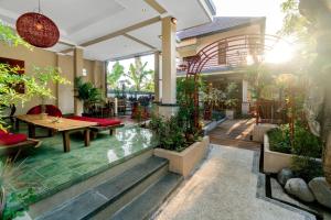 une terrasse avec des tables et des plantes en pot dans l'établissement Metteyya Healing House, à Ubud