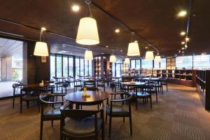 a dining room with tables and chairs and windows at Hotel Binario Saga Arashiyama in Kyoto