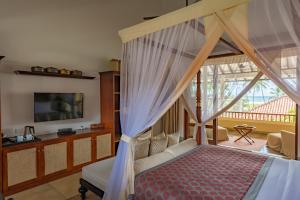 a bedroom with a canopy bed and a tv at Taru Villas The Long House - Bentota in Bentota