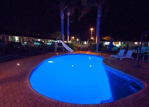 una piscina iluminada de azul por la noche en James Street Motor Inn, en Toowoomba