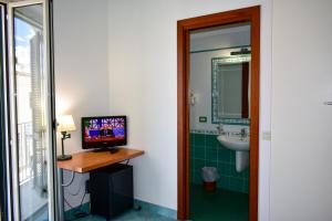 a bathroom with a sink and a television on a table at Hotel Amyclae in Sperlonga