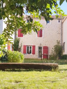 ソー・ドゥ・ヴォクリューズにあるChambres entre Ventoux et luberonの赤いシャッターとベンチが前にある家