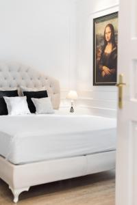 a white bedroom with a large white bed with a painting at La Canea Canvas 1 in Chania Town