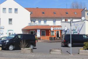 dos autos estacionados en un estacionamiento frente a un edificio en Hotel Riedel, en Zittau
