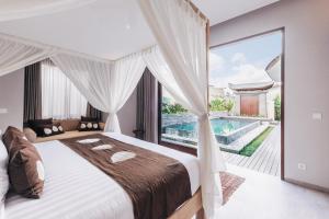 a bedroom with a large bed and a large window at Daun Lebar Villas in Payangan