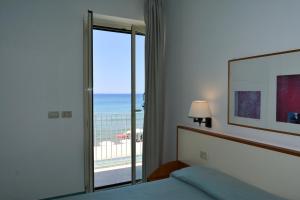 a bedroom with a bed and a view of the ocean at Hotel Amyclae in Sperlonga