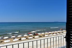 a beach with umbrellas and people in the ocean at Hotel Amyclae in Sperlonga