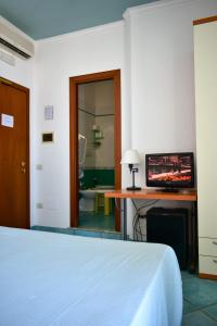 a bedroom with a bed and a desk with a television at Hotel Amyclae in Sperlonga