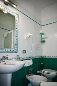 a bathroom with a sink and a toilet and a mirror at Hotel Amyclae in Sperlonga