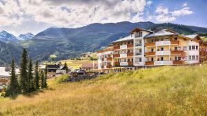 a hotel on a hill with mountains in the background at Hotel Castel - pure Lebensfreude in Serfaus