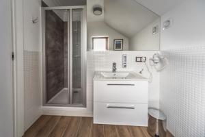 a white bathroom with a sink and a shower at Willa Feria in Międzyzdroje