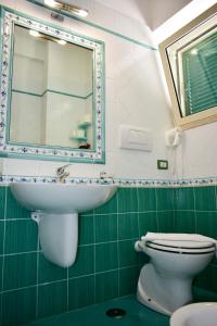 a bathroom with a sink and a toilet and a mirror at Hotel Amyclae in Sperlonga