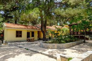 una pequeña casa amarilla con un árbol y un patio en Platres Valley Houses en Platres