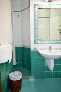 a green and white bathroom with a sink and a mirror at Hotel Amyclae in Sperlonga