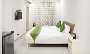 ein Schlafzimmer mit einem weißen Bett und grünen Kissen in der Unterkunft Itsy By Treebo - Kamron in Chandīgarh