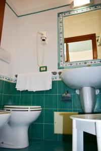 a bathroom with a sink and a toilet and a mirror at Hotel Amyclae in Sperlonga
