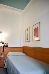 a bedroom with two beds and two pictures on the wall at Hotel Amyclae in Sperlonga