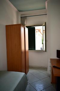 een slaapkamer met een bed, een houten kast en een raam bij Hotel Amyclae in Sperlonga