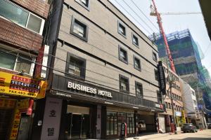 Business Hotel Busan Station في بوسان: مبنى به فندق أعمال على شارع المدينة