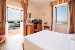 una camera d'albergo con un letto e una grande finestra di Hotel Sirmione a Sirmione