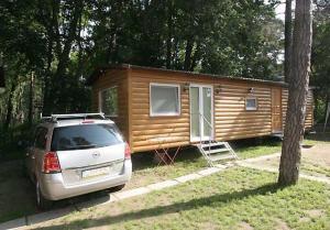 a small cabin with a car parked in front of it at Wynajem domkow "Mala Holandia" in Krynica Morska