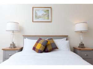 um quarto com uma cama branca e 2 candeeiros em Historic Stone Built 4BR Cottage for 8 W/Parking em Edimburgo
