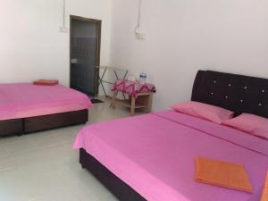 twee bedden in een kamer met roze lakens bij Delimah guesthouse in Kuala Tahan