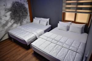 two beds with white pillows and pillows in a room at Business Hotel Busan Station in Busan