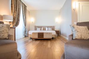 a bedroom with a bed and two chairs and a couch at Grand Hotel Terme Sirmione in Sirmione