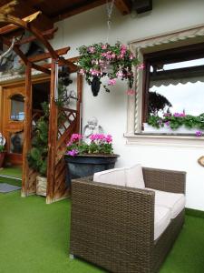 eine Terrasse mit einem Korbstuhl und Blumen im Garten in der Unterkunft Gasthof Geierwallihof in Vent