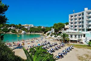 uma praia com cadeiras e pessoas na água em Hotel Playa Santandria Adults Only em Cala Santandria