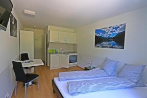 1 dormitorio con cama, escritorio y cocina en b&b River Inn en St. Moritz