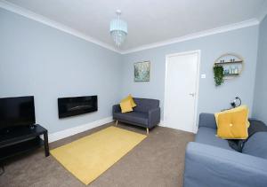 a living room with two blue couches and a television at Wingfield Lodge - Near Clay Cross in Chesterfield