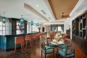a restaurant with a bar and tables and chairs at Manoir Des Arts Hotel in Hai Phong