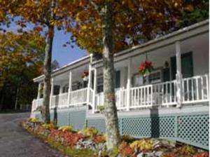 a white house with trees in front of it at Mount Battie Inn in Lincolnville