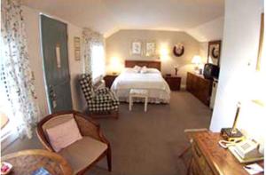 ein Schlafzimmer mit einem Bett und einem Stuhl in einem Zimmer in der Unterkunft Mount Battie Inn in Lincolnville