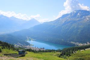 un tren en una pista cerca de un lago en las montañas en b&b River Inn, en St. Moritz