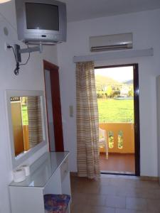 a living room with a television and a mirror at Rooms Leonidas in Kissamos